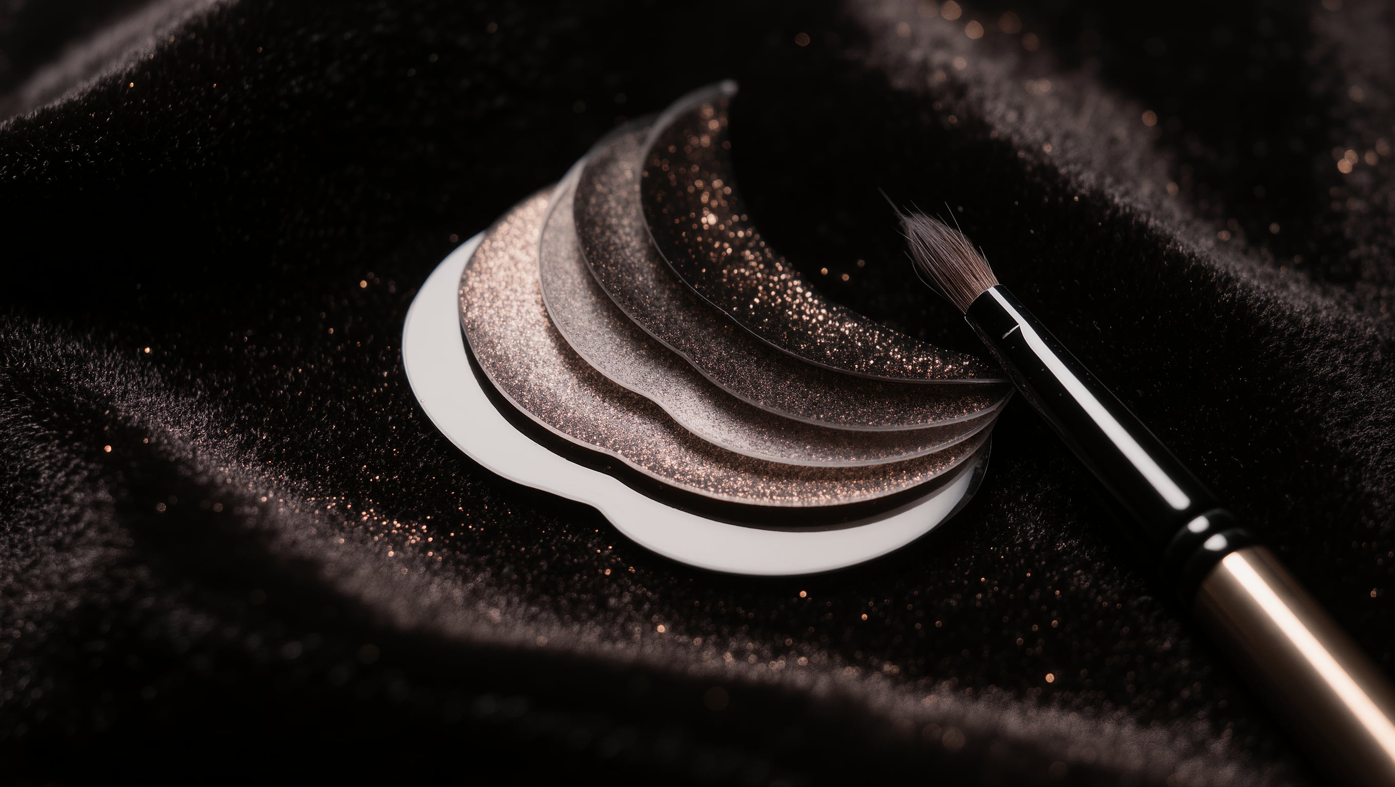 Silikonpads und eine feine Applikationsbürste für Wimpern auf schwarzem Samt im punktuellen Licht